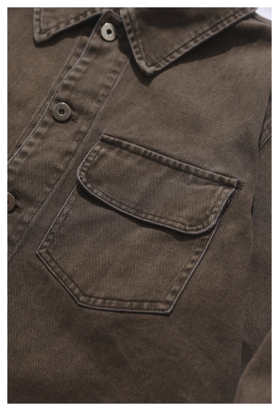 Close-up of the brown shirt's large chest pocket with a curved flap and visible stitching.