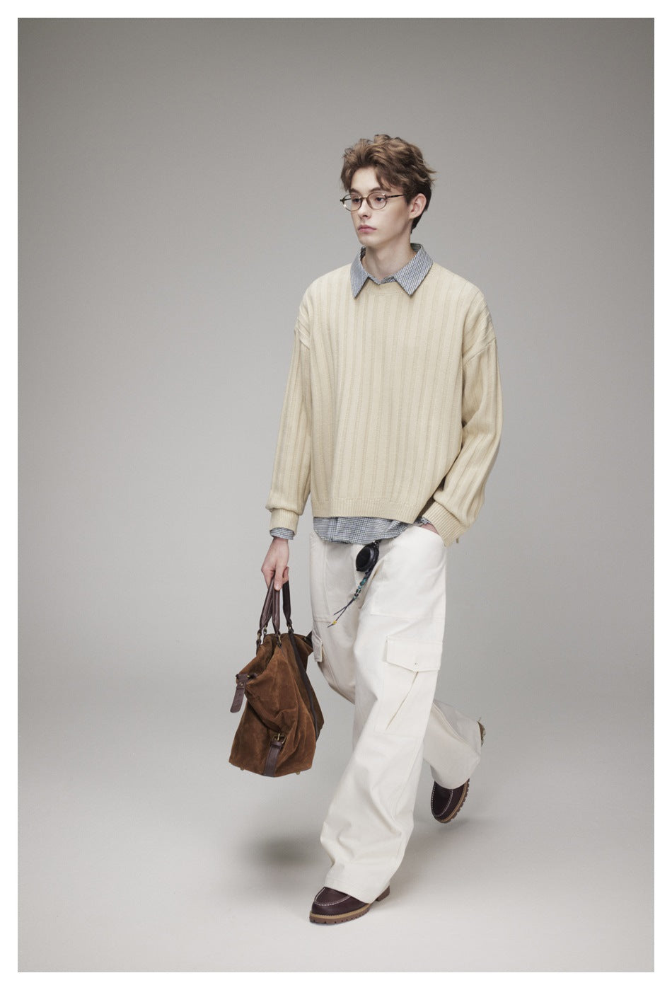 Model wearing a cream ribbed sweater over a checked shirt with white cargo trousers.