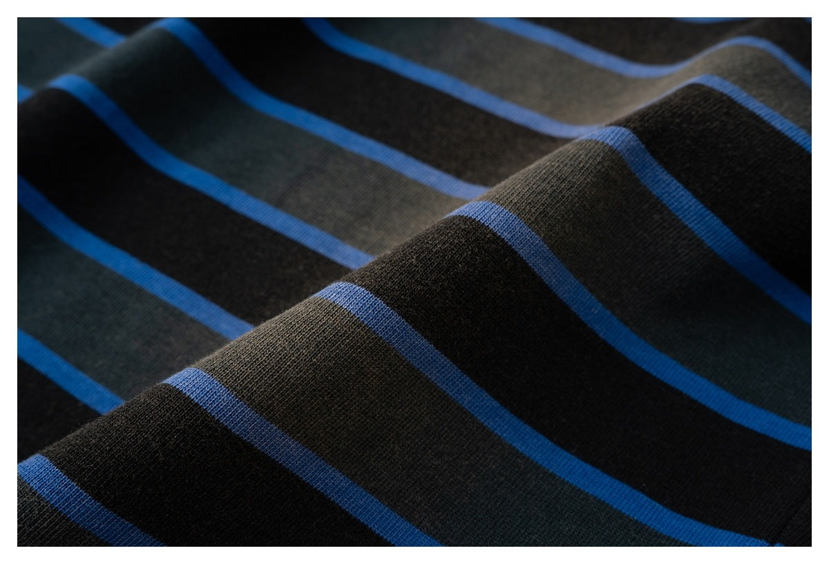 Close-up of black and charcoal shirt fabric with bright blue stripes draped into soft folds.