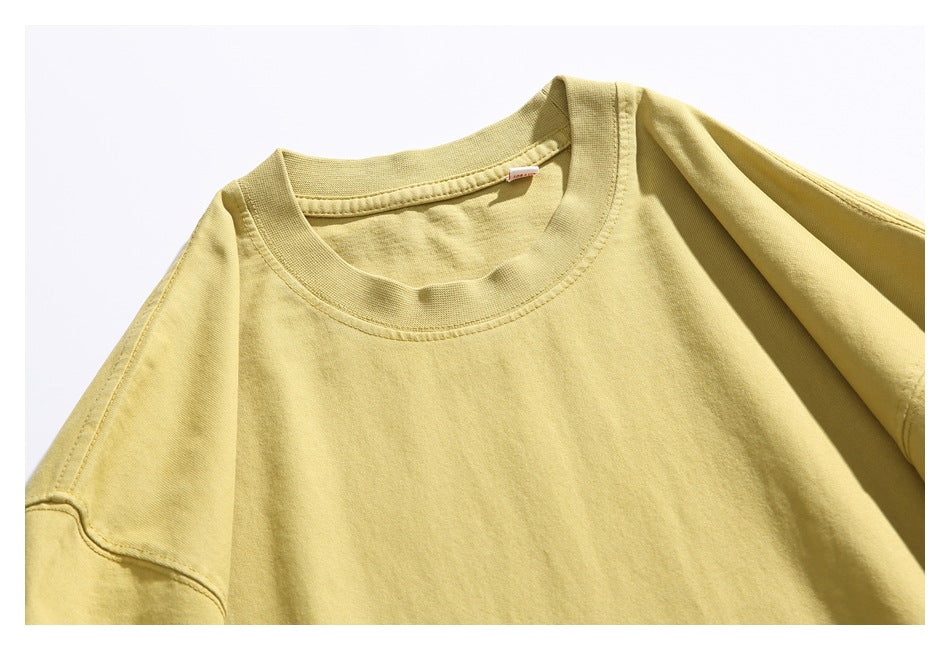 Close-up of a pale yellow T-shirt showing its crew neck, shoulder seam, and upper chest.