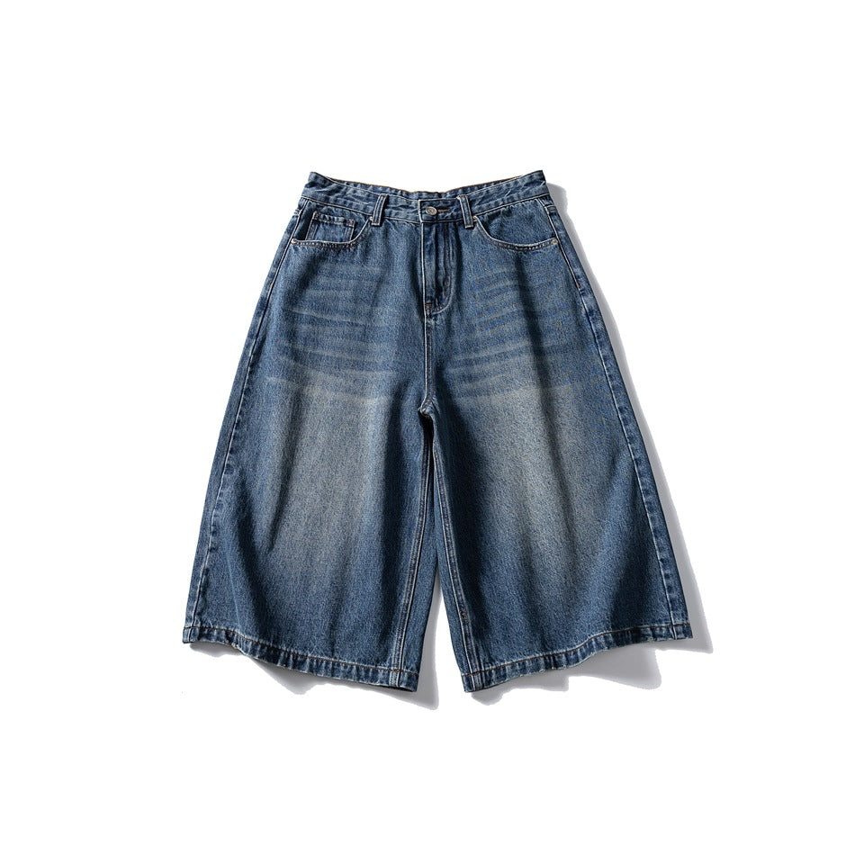 Front of washed blue wide-leg knee-length denim shorts with faded whiskering, belt loops and zip fly