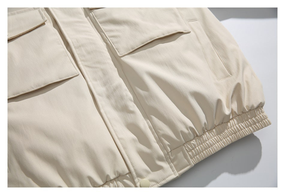 Close-up of the ivory jacket's lower front, showing flap pockets, a vertical pocket and an elasticated hem.