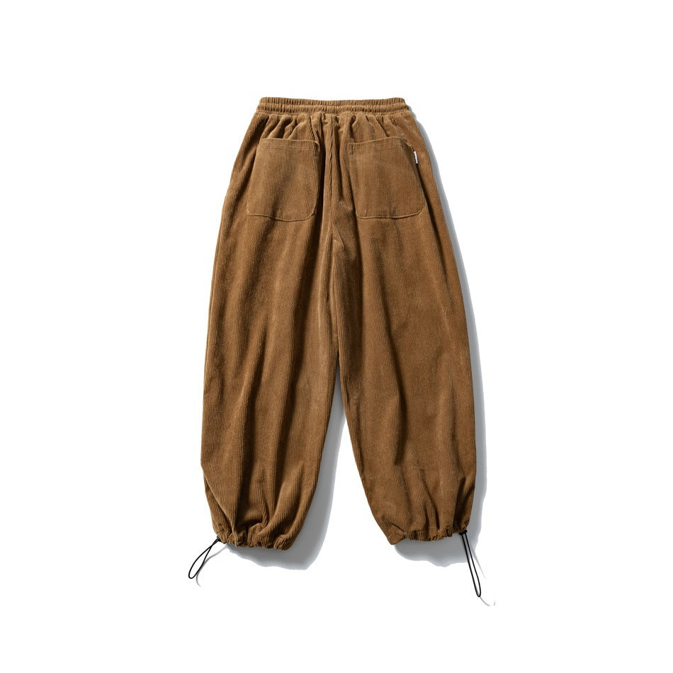 Front view of brown corduroy jogger trousers with an elastic waistband, two front pockets, and adjustable drawcord cuffs.