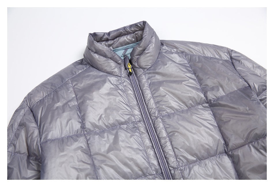 Close-up of a gray quilted jacket front, showing its padded collar, center zipper, and yellow zipper pull.