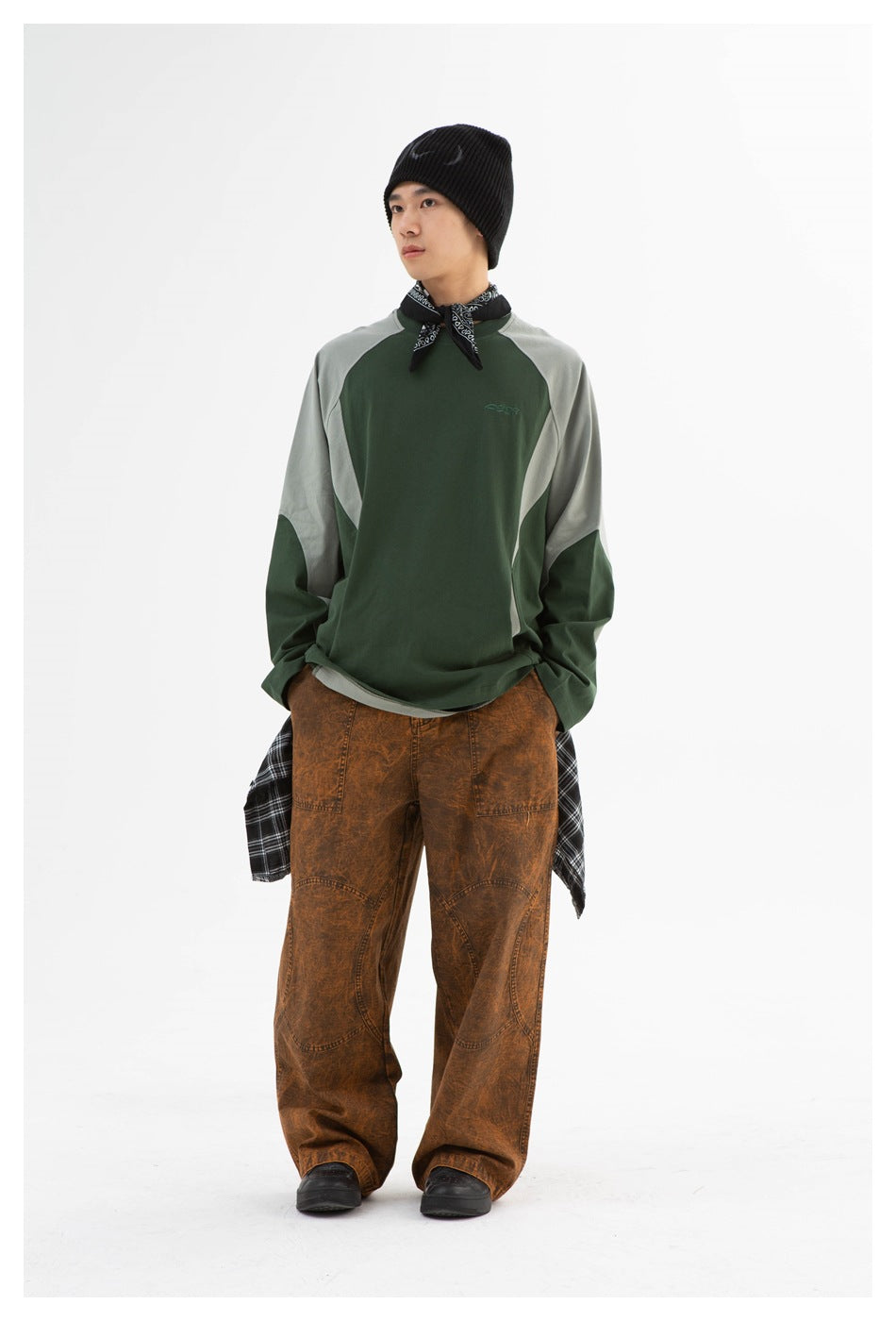 Model wearing the green long-sleeve color-block top with a black beanie, bandana, brown washed wide-leg pants and plaid shirt
