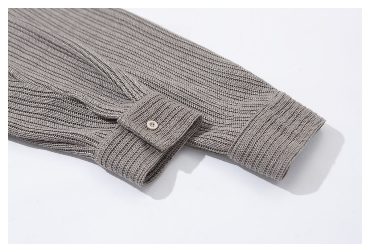Close-up of a gray ribbed sleeve cuff with a button tab and button closure.