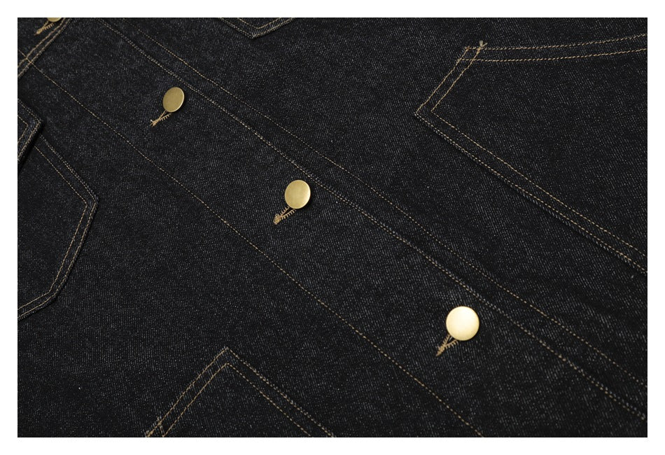 Close-up of dark indigo denim with tan stitching, brass buttons and visible pocket edges.