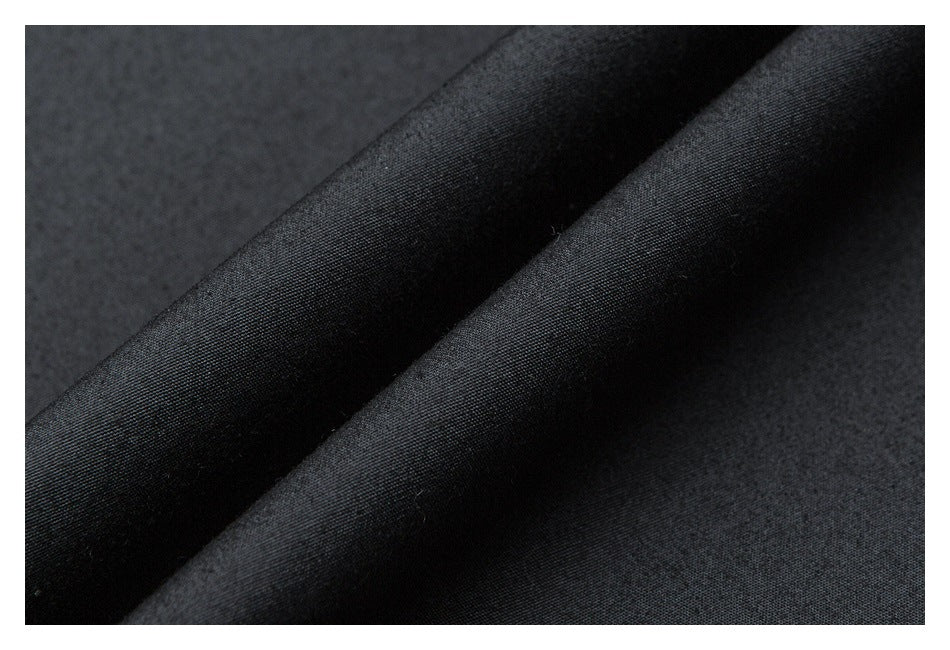 Extreme close-up of dark fabric folded into soft ridges, showing its surface texture.