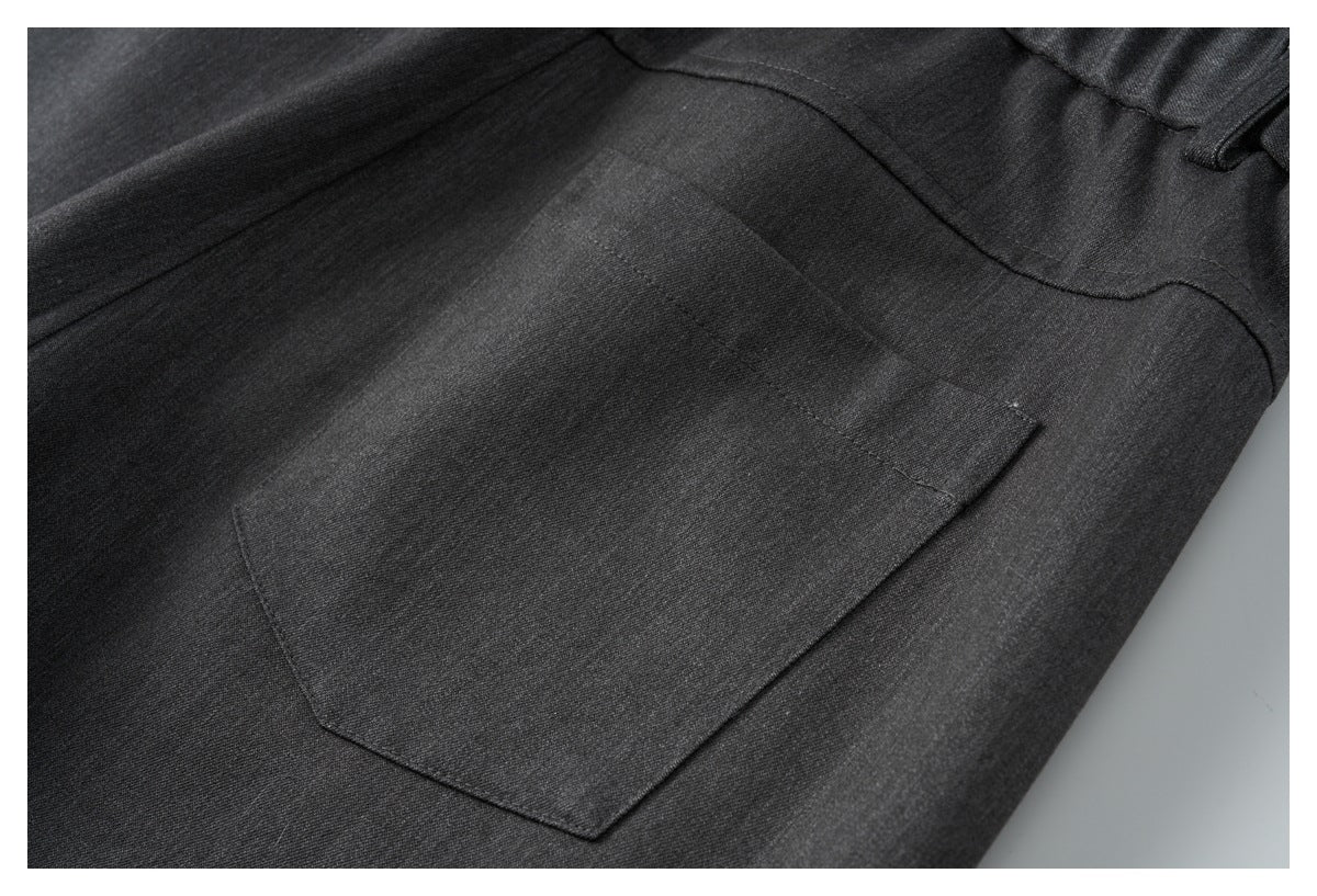Close-up of a stitched rear patch pocket on charcoal trousers.