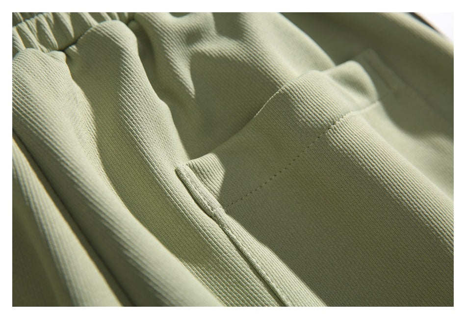 Close-up of a patch pocket and stitching on sage green pants.
