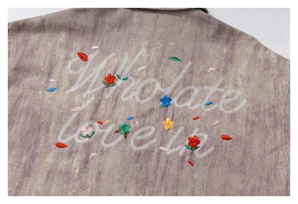 Back detail of a mauve mottled jacket embroidered with “Welcome love” and colorful flowers.
