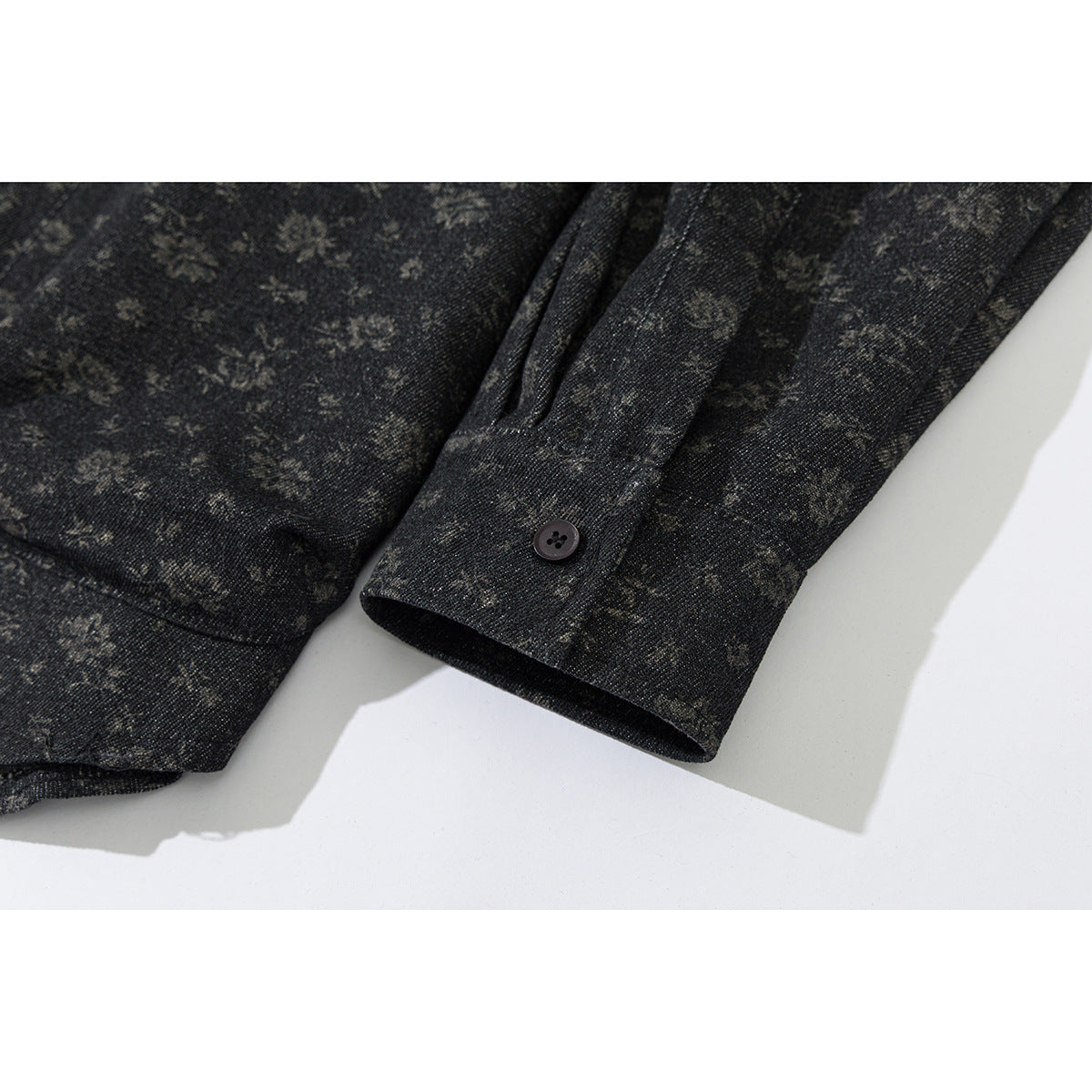 Close-up of the dark floral-patterned jacket sleeve and buttoned cuff.