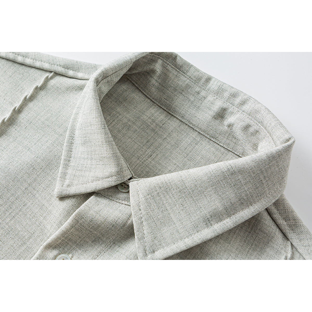 Close-up of a light gray shirt collar, button, and textured fabric.