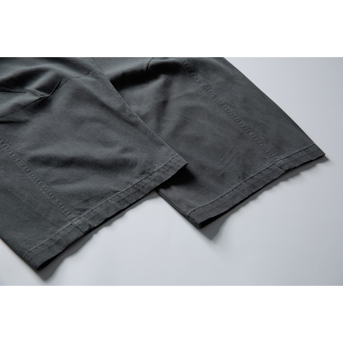 Close-up of charcoal pants showing the wide leg hems and stitched seams.