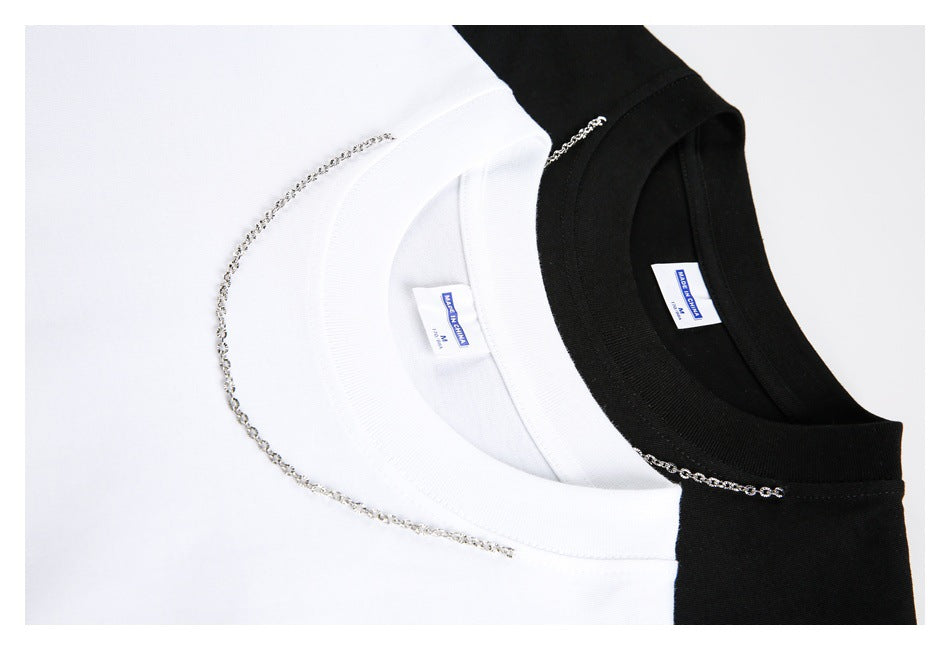 Close-up of white and black T-shirt collars with silver chain details and sewn-in neck labels.