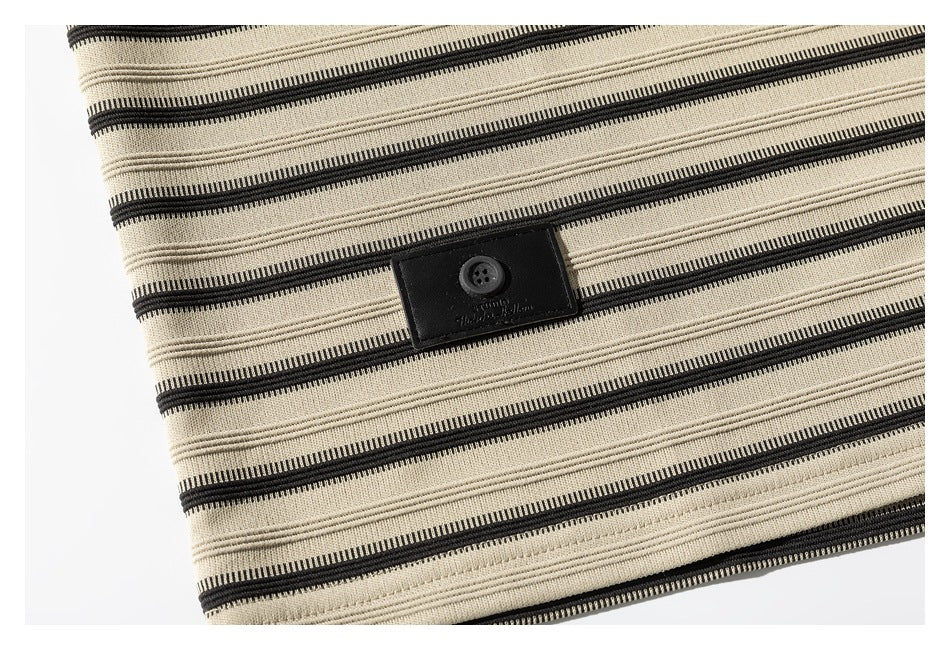 Close-up of the beige-and-black striped fabric and a small black button tab near the hem.