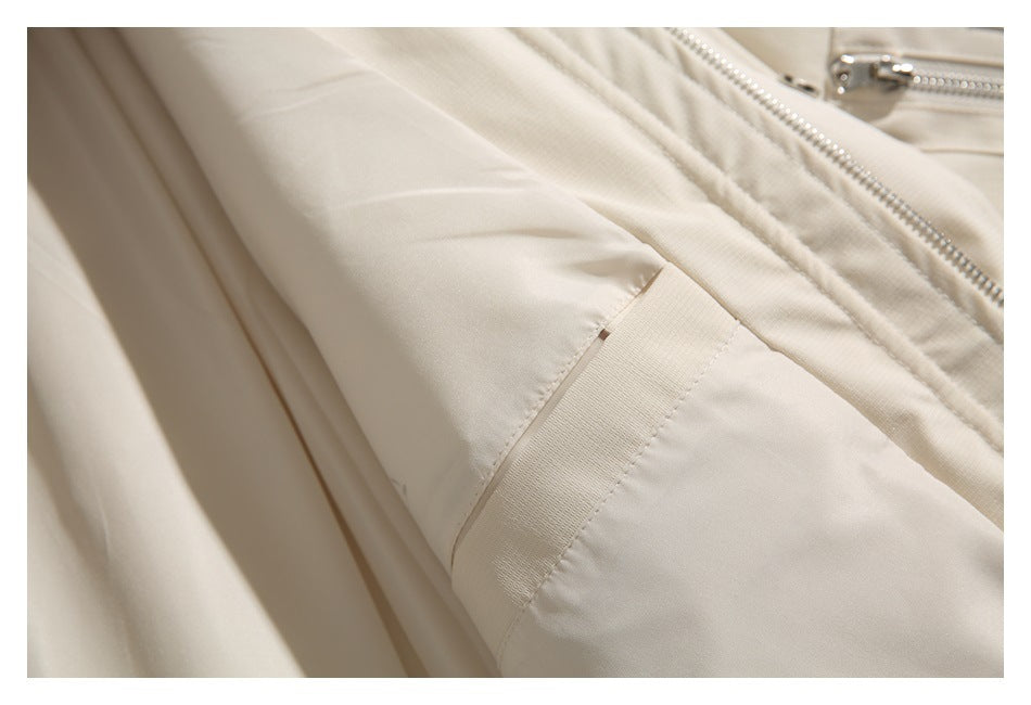Close-up of a beige jacket sleeve cuff beside the front zipper.