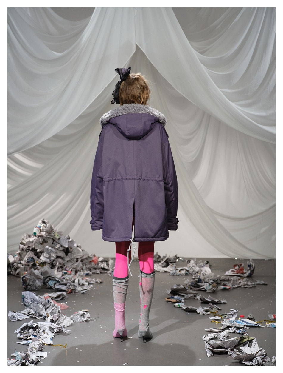 Back view of a model wearing a dark purple parka with a hood and gray plush collar trim.