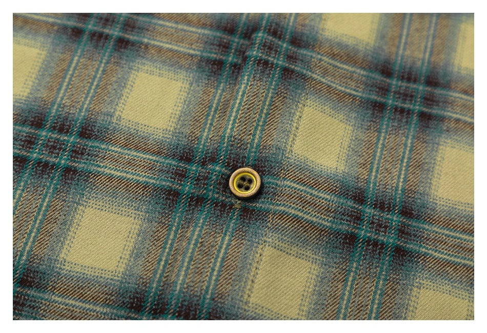 Macro view of the olive and dark plaid fabric and a small four-hole button.