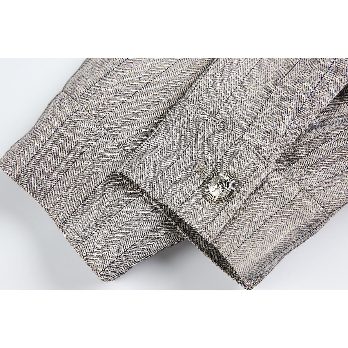 Close-up of a buttoned cuff and hem on a light gray pinstriped jacket.