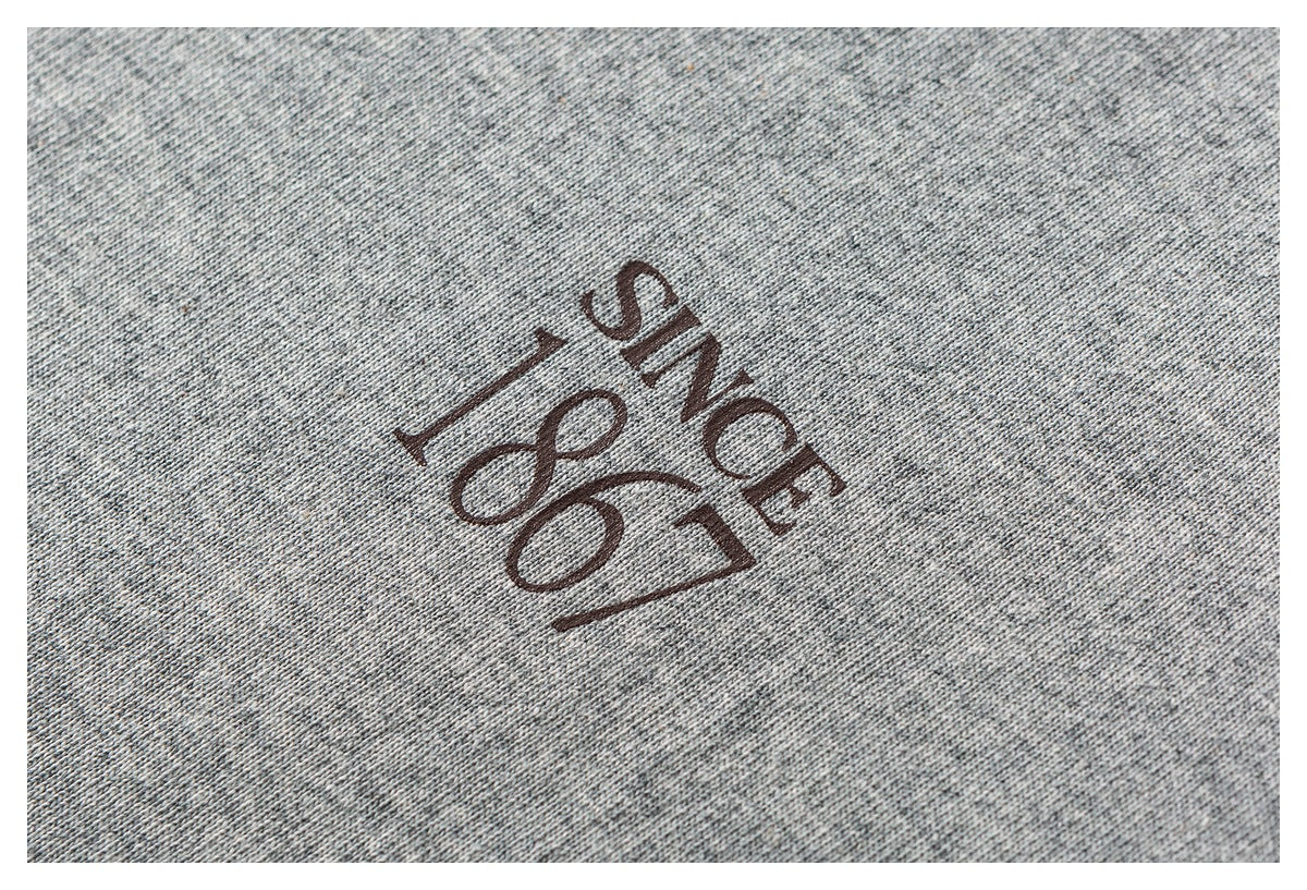 Close-up of heather-gray fabric with a dark brown “Since 1867” print.