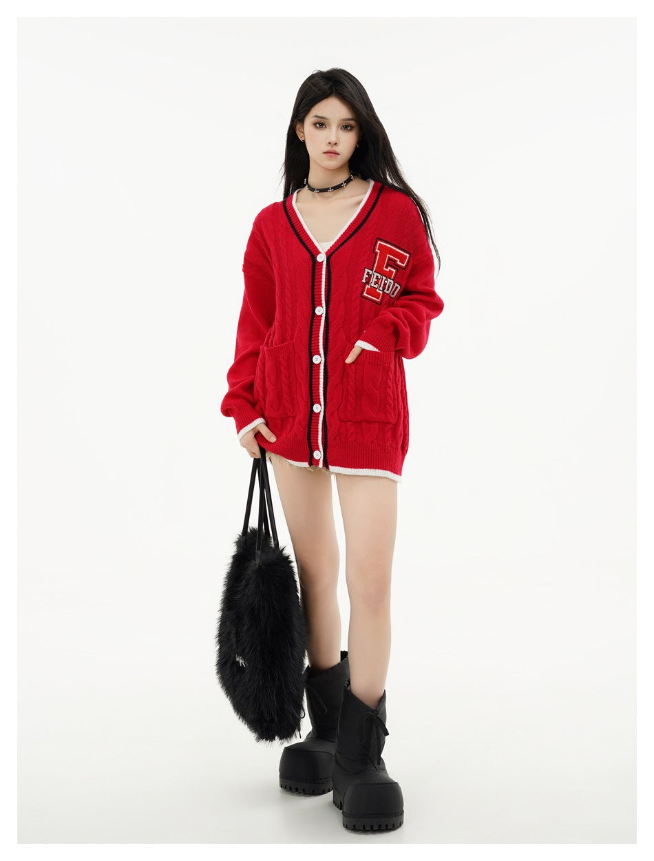 Full-length model wearing a red oversized cable-knit cardigan with striped trim, patch pockets and a letter patch.