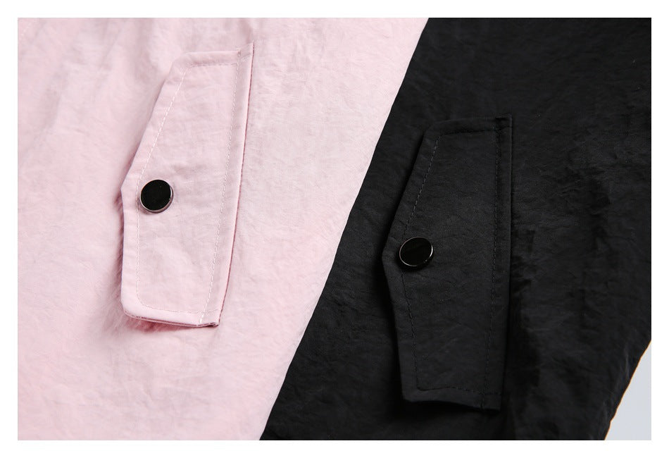 Close-up of pink and black jacket sleeve tabs with round buttons.