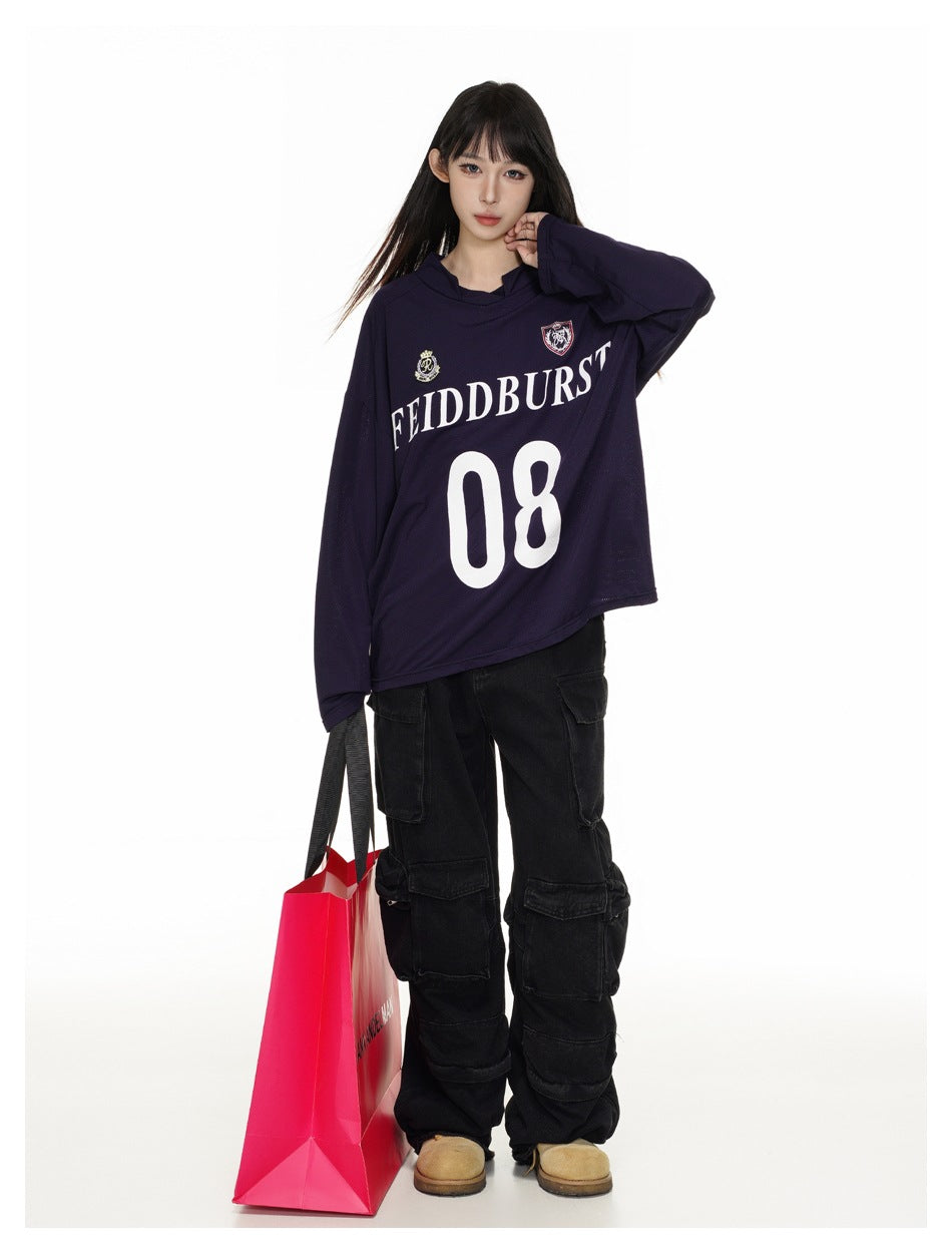 Model wearing a dark navy hooded jersey with crest graphics and a large white 08, holding a bright pink shopping bag.