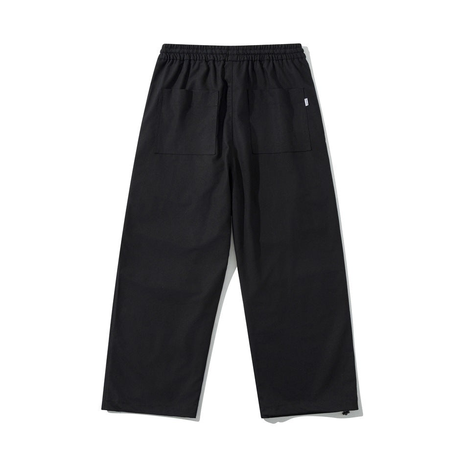 Black wide-leg pants back view with two large patch pockets, elastic waistband and hem toggles