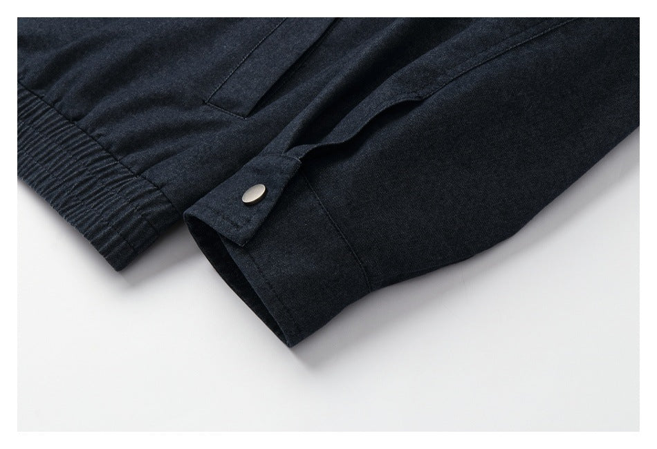 Close-up of a dark jacket sleeve cuff with a snap-button tab and stitched seam.