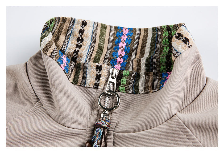 Close-up of a beige jacket's multicolor striped collar trim and silver zipper pull.