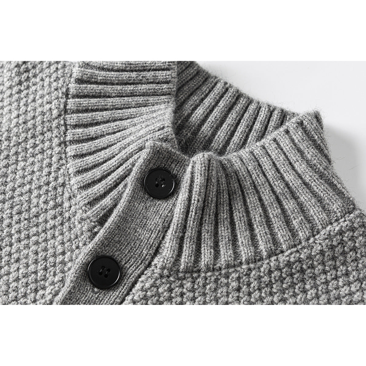Close-up of a gray knit cardigan’s ribbed stand collar and black buttons.