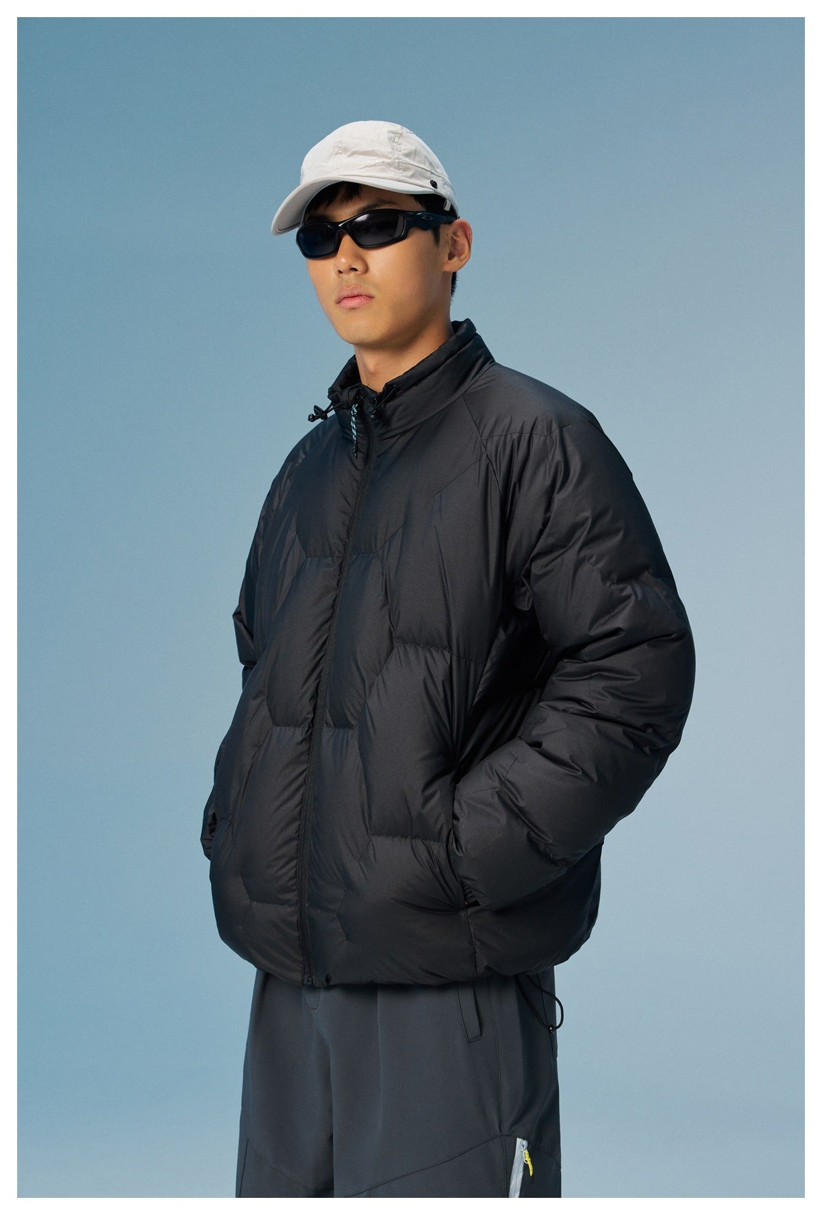 Closer view of a model wearing a black quilted jacket with a high drawcord collar and zip front.