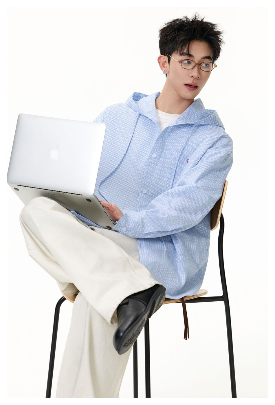 Model seated with a laptop, wearing a light blue fine-check hooded button-up shirt.
