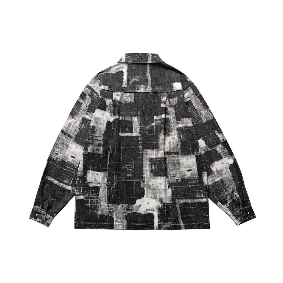 Back view of black, gray and white abstract printed jacket with yoke seam and snap cuffs, flat lay