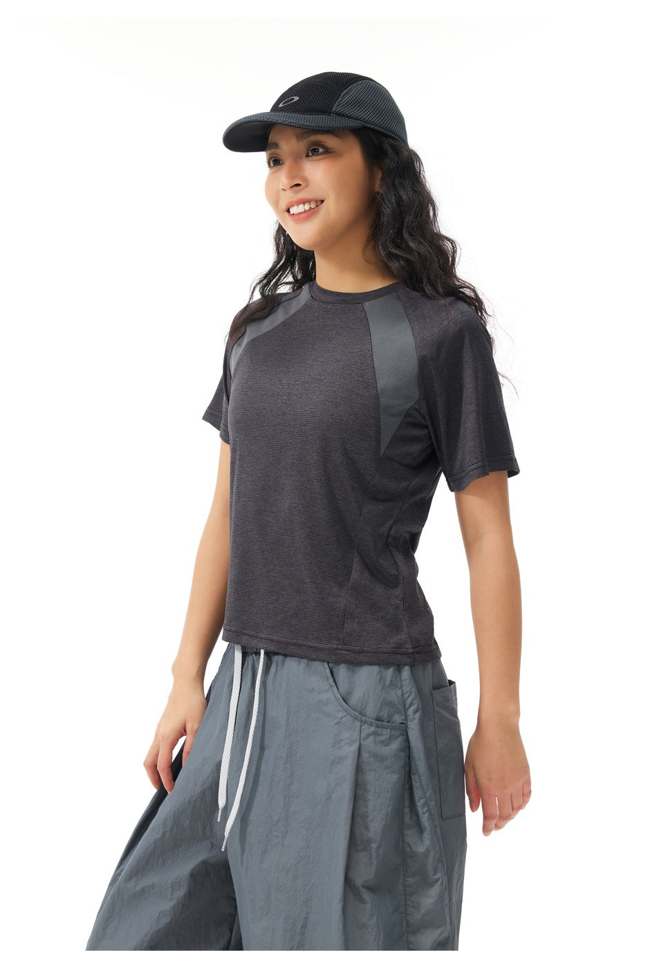 Three-quarter view of a model wearing a charcoal raglan T-shirt and loose slate-gray pants.