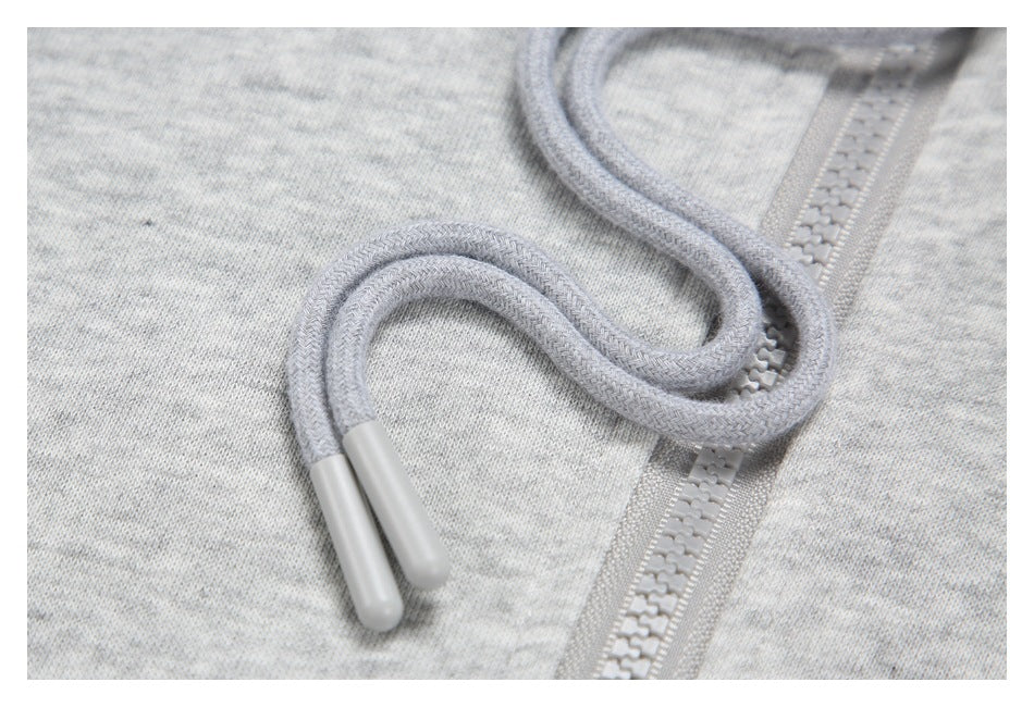 Close-up of gray drawcords and a matching zipper on light heather-gray fabric.