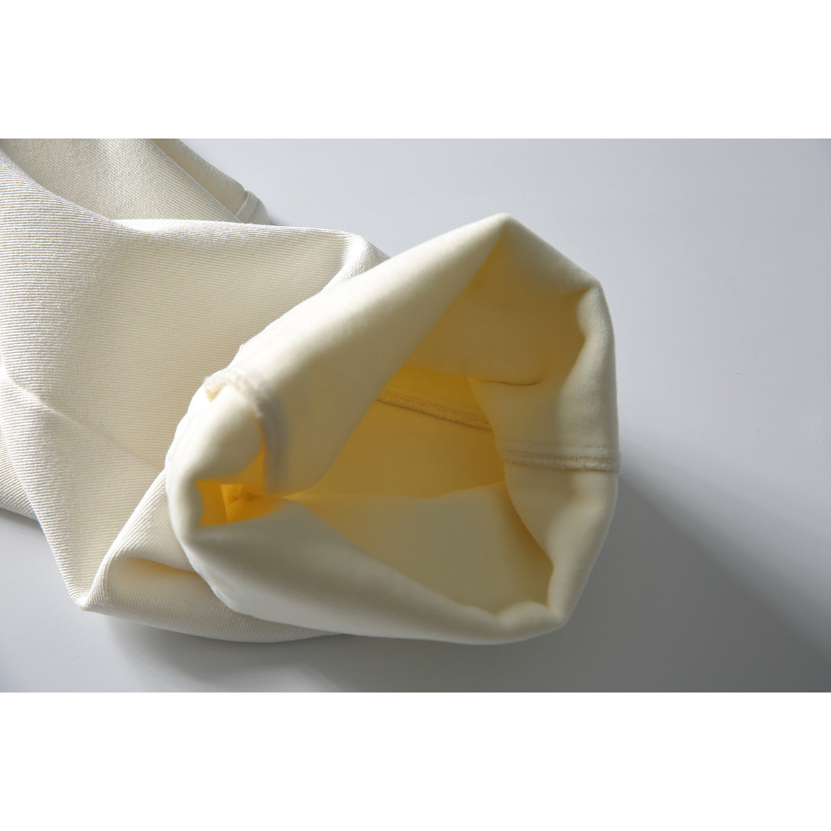 Off-white trouser leg opening turned inside out to show the inner fabric and stitching.