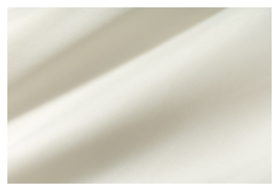 Close-up showing the fine woven texture of cream-colored garment fabric.