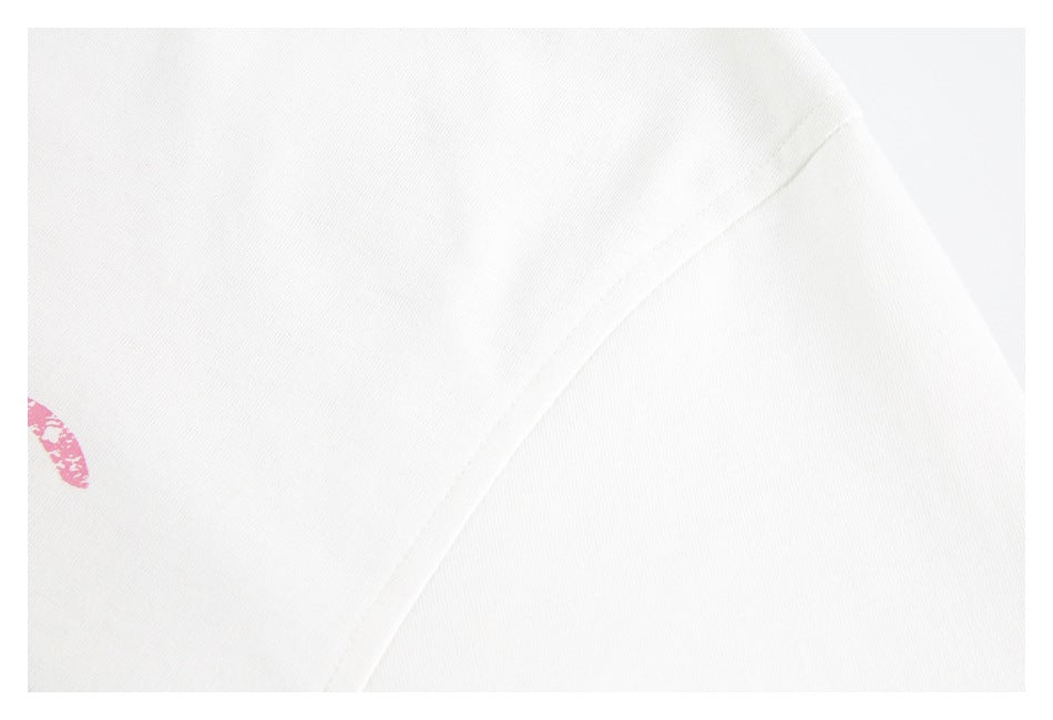 Close-up of a white T-shirt shoulder seam with a small edge of the pink print visible.