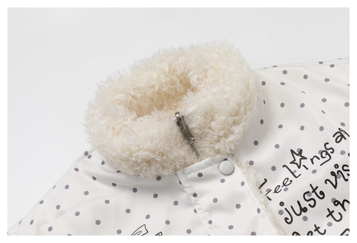 Close-up of an ivory jacket with gray polka dots, a fluffy cream collar, and a metal zipper.