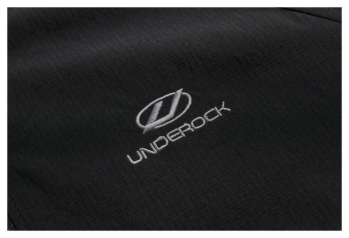 Close-up of a silver embroidered emblem and UNDEROCK lettering on black jacket fabric.