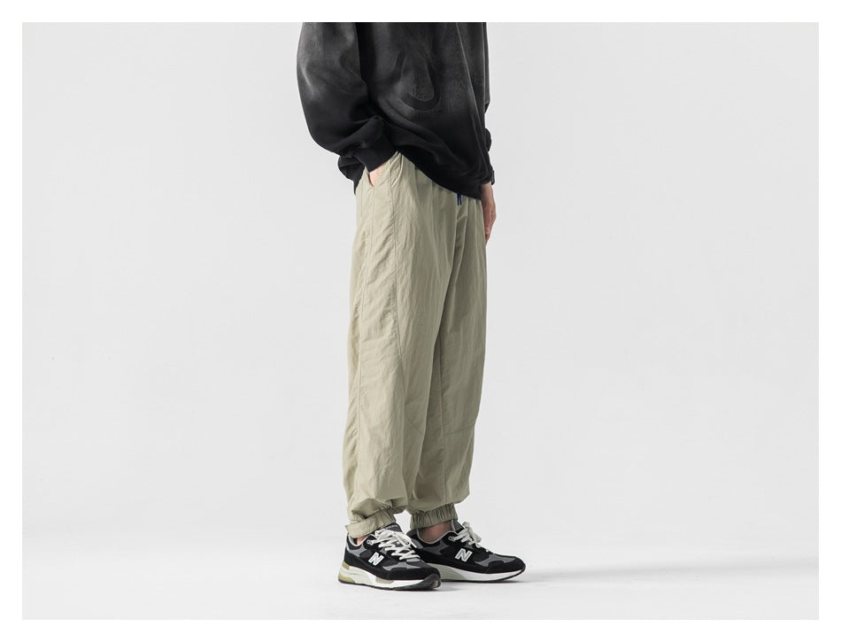 Side view of person wearing khaki jogger pants with elastic cuffs, dark sweatshirt and black sneakers