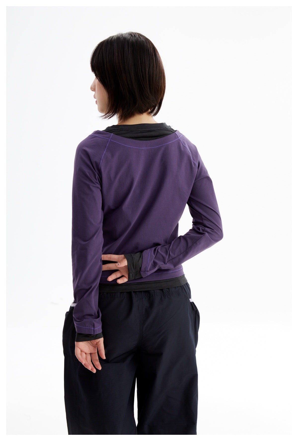 Back view of a person wearing a purple long-sleeve top with contrast stitching over a black layer.