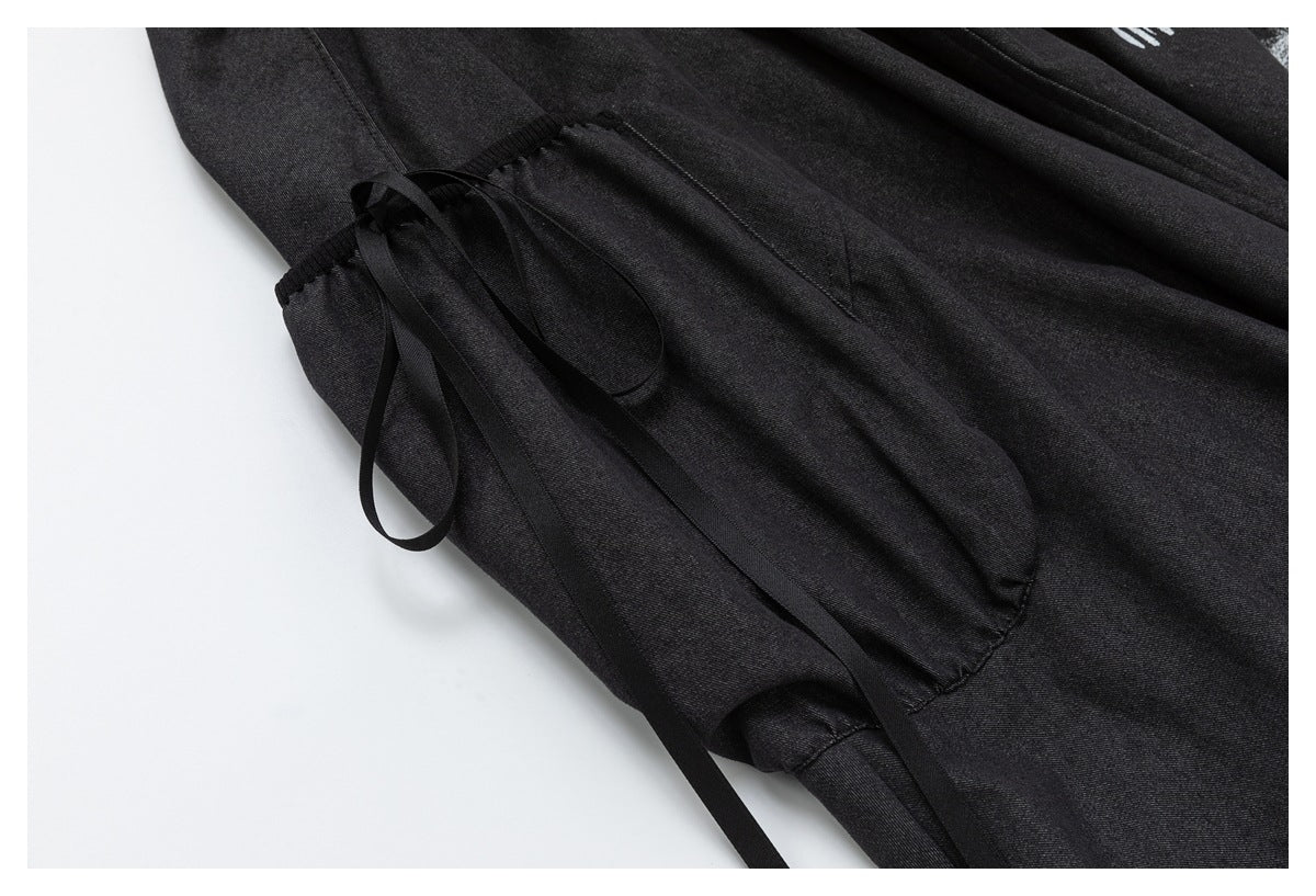 Close-up of a skirt pocket with long black ribbon ties and stitched edges.