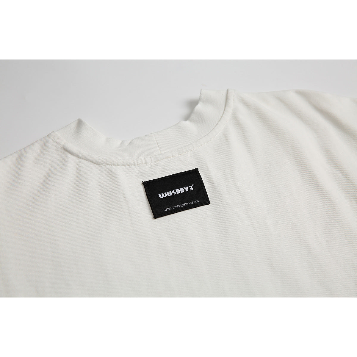 Close-up of an off-white T-shirt neckline with a black sewn-in label.