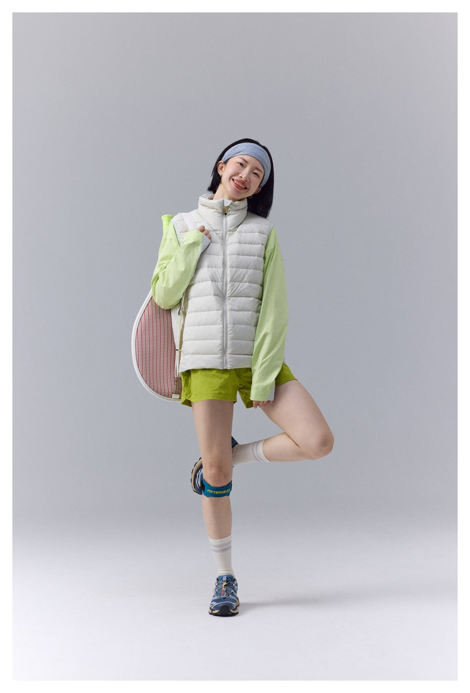 Woman wearing a white quilted vest over a light green top and lime shorts, shown full-length from the front.