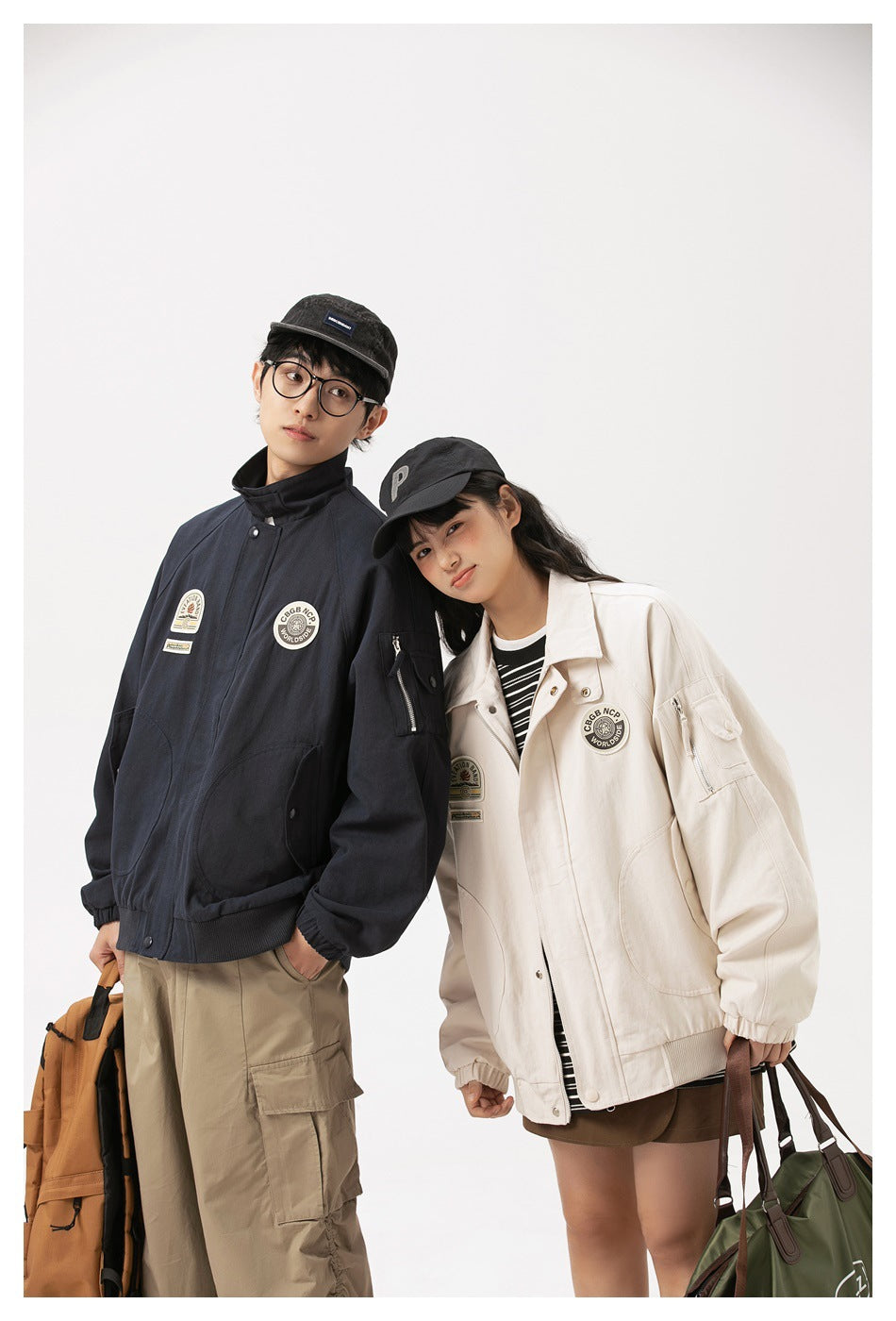 Two models pose in navy and ivory zip-front jackets with high collars, patches, and roomy pockets.