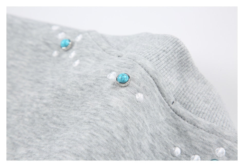 Close-up of turquoise buttons and white accents beside the ribbed collar of a heather gray garment.