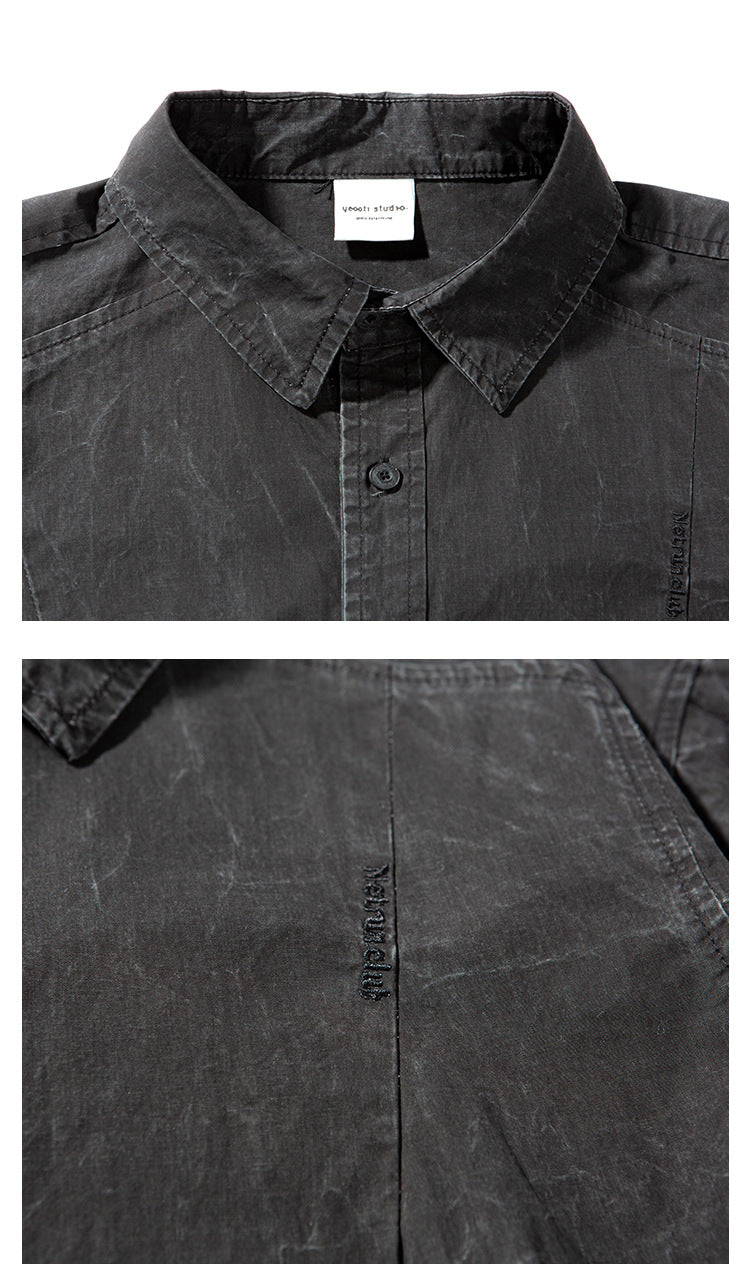 Close-up of a charcoal shirt's pointed collar, button placket and small tonal chest embroidery.